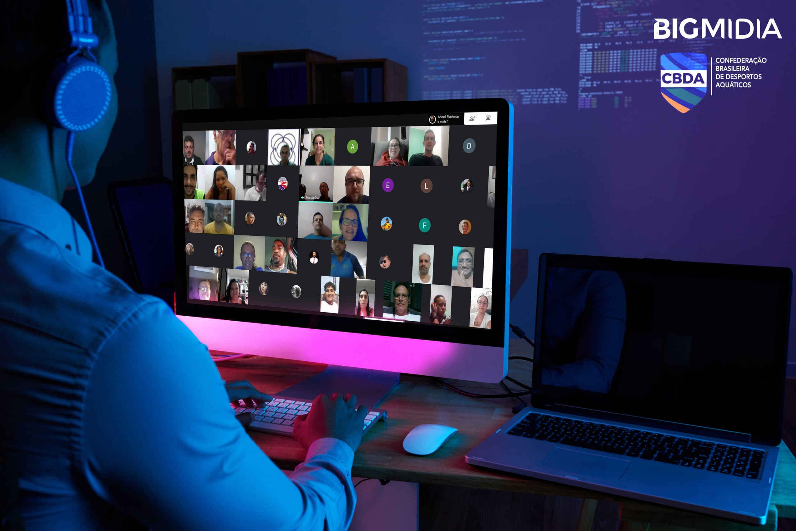 Imagem com uma pessoa de frente para um computador. Na tela do computador estão os participantes do curso online da Bigmidia.